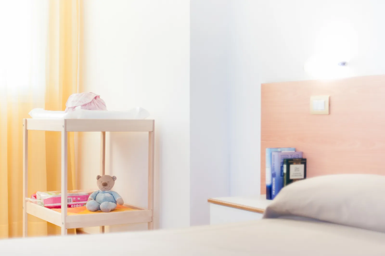 Dettaglio di una camera da letto con comodino e un fasciatoio per neonati sullo sfondo